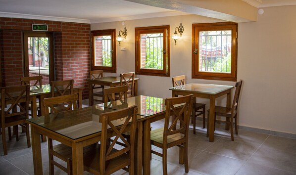 A dining area with brick walls, wooden tables and chairs, and large windows with views of greenery. - Ottoman's Pearl Hotel (Istanbul)