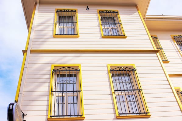A building with three windows, each with yellow frames and black bars.