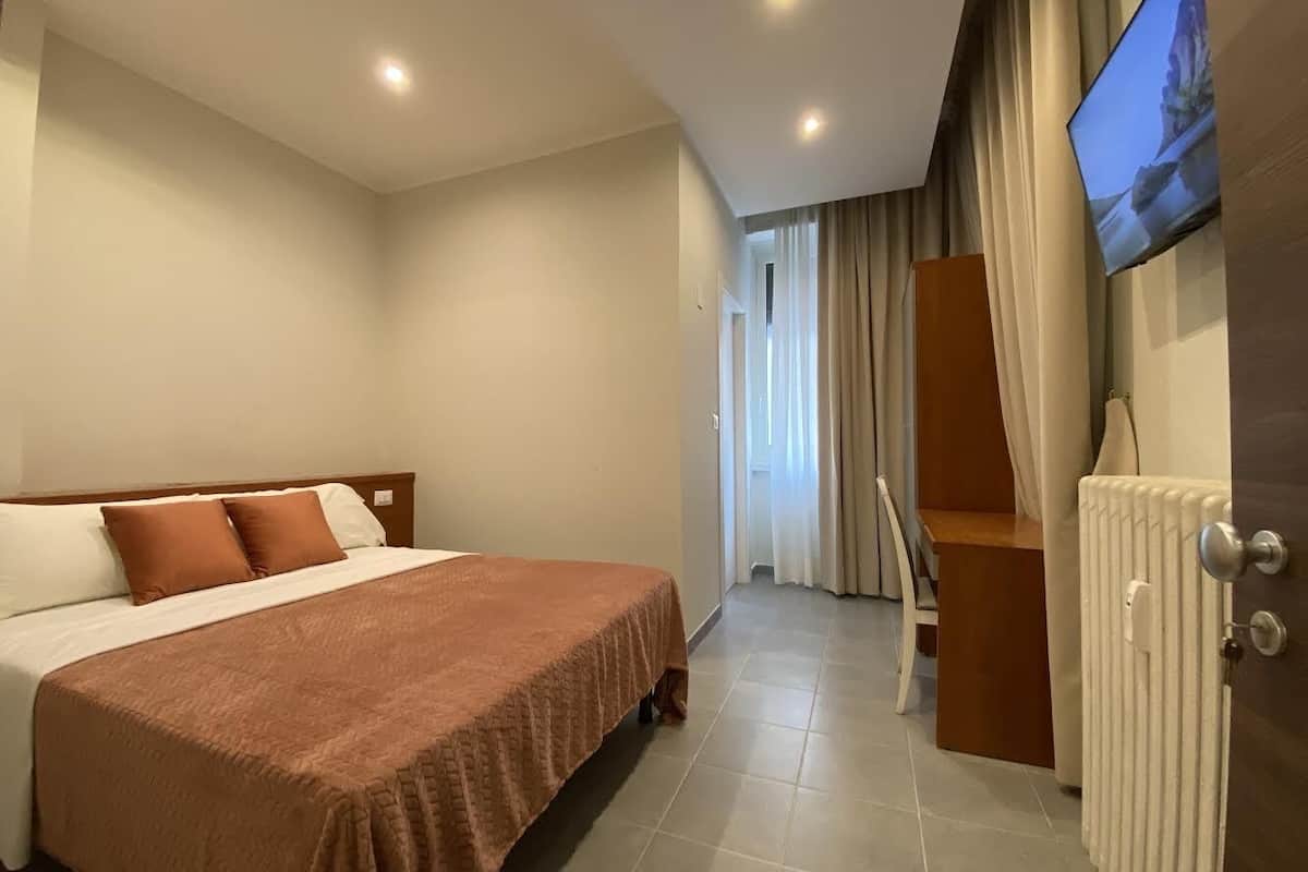 Een hotelkamer met een groot bed, een aan de muur bevestigde televisie en uitzicht op het buitenlands landschap door het raam.