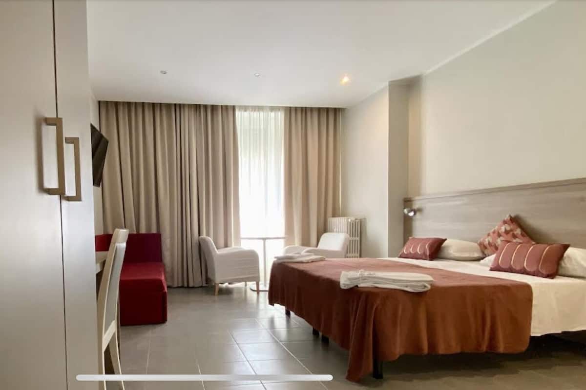 Een hotelkamer met een bed, bureau, stoel en televisie.