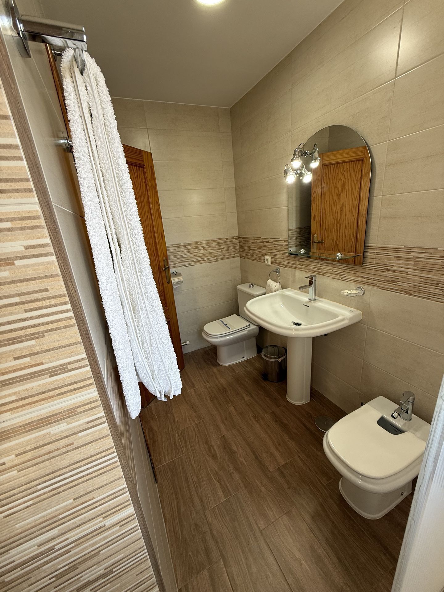 Un bany amb terra de fusta, un rentapeus blanc, un vàter i un bidet.