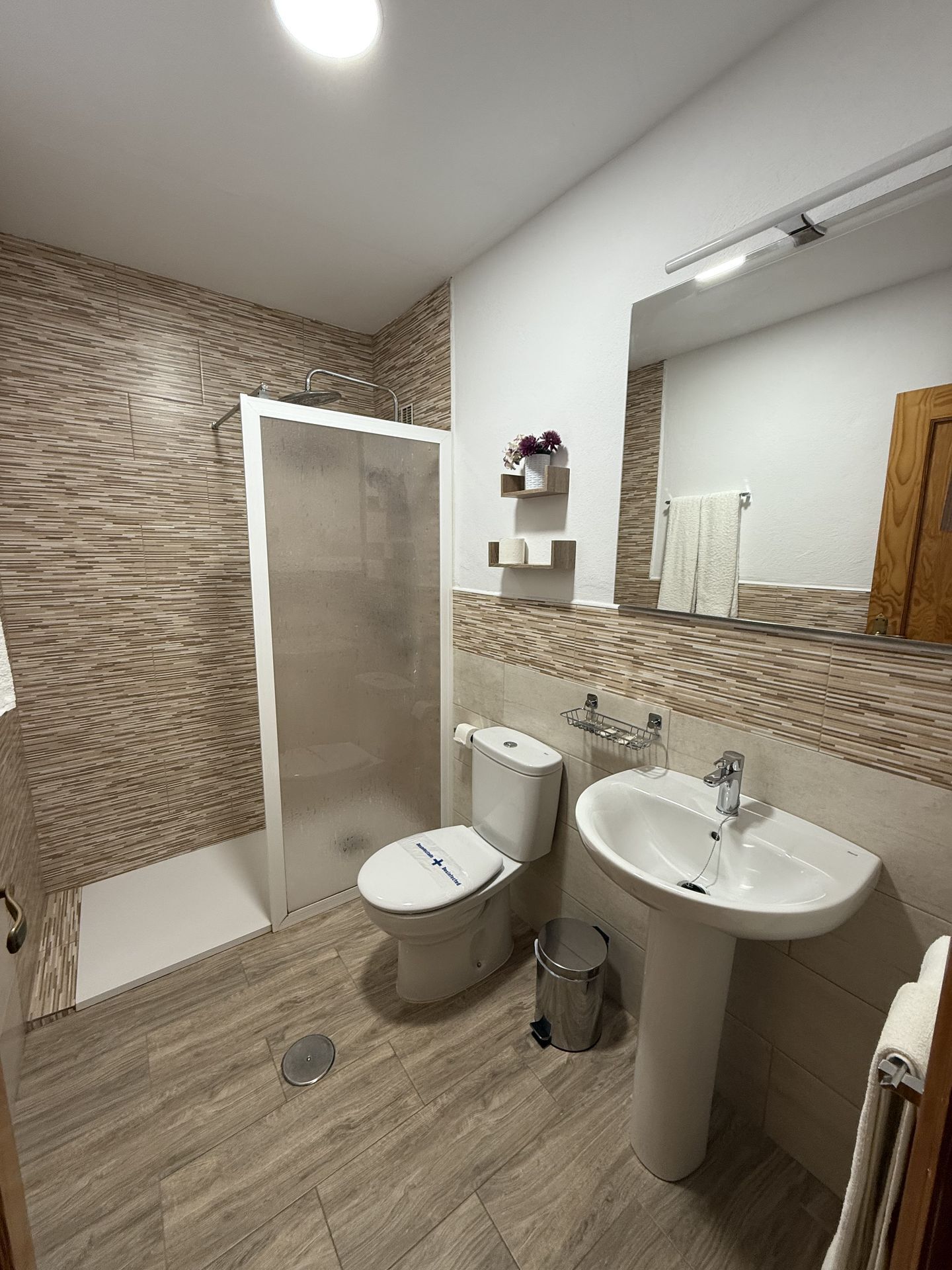 A modern bathroom with a shower, toilet, and sink.