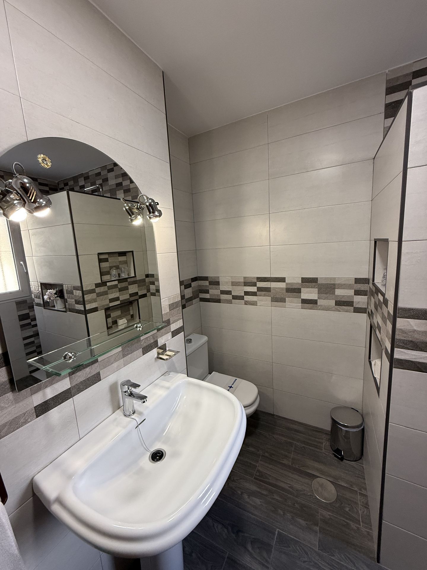 A modern bathroom with a glass sink, a toilet, and a shower area.