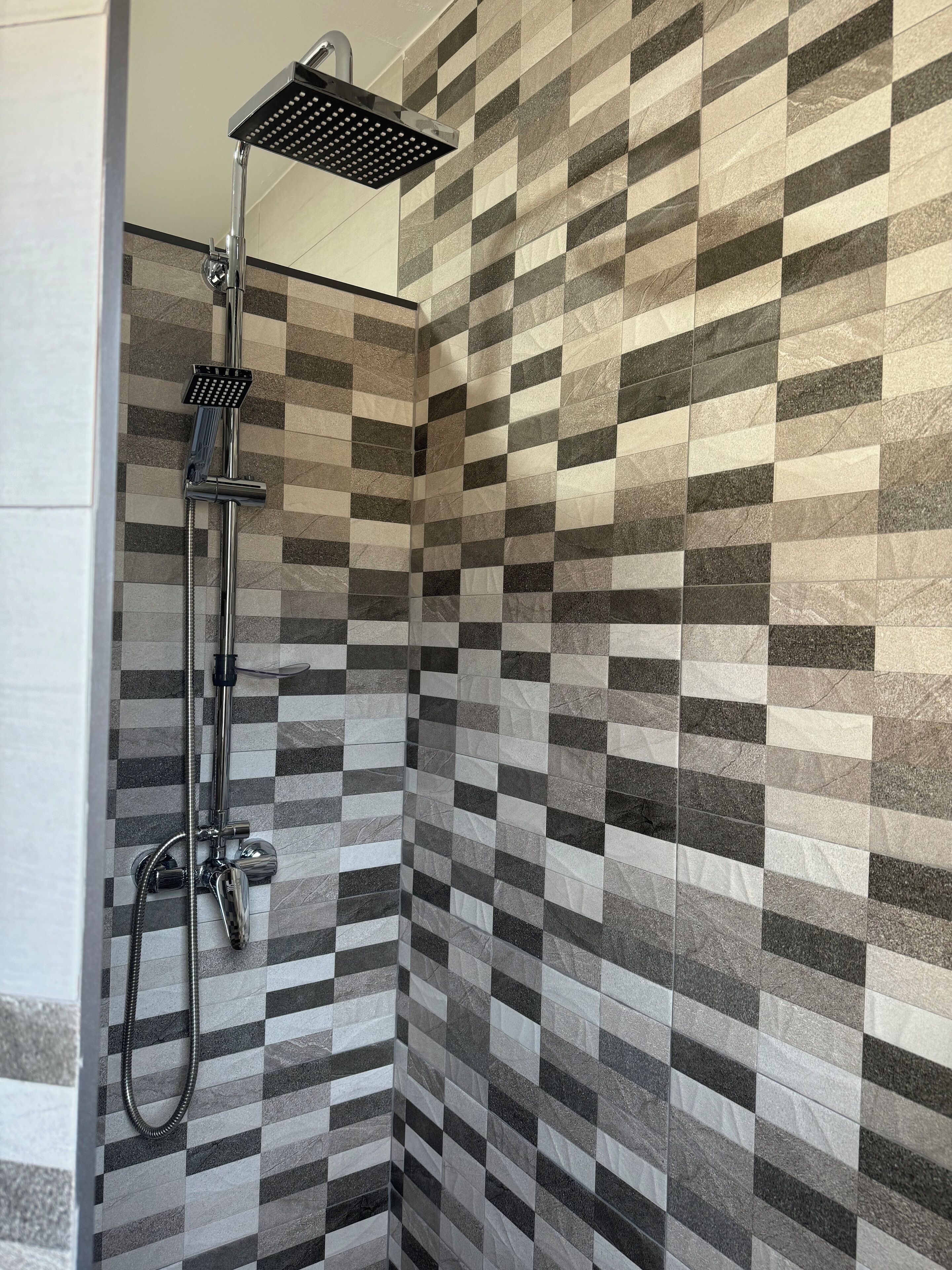 A shower with a modern design, featuring a checkered tile pattern on the walls.