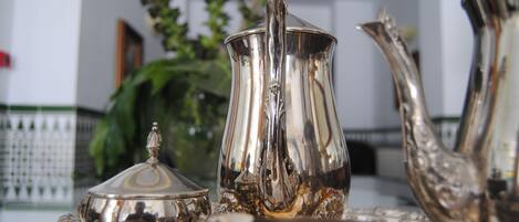 A silver tea set with a teapot, sugar bowl, and creamer on a table.