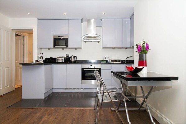 A modern kitchen with grey cabinets, stainless steel appliances, and a central island with a sink and stools.