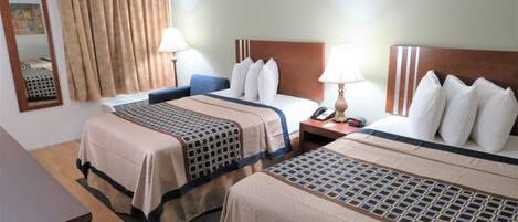 Een hotelkamer met twee bedden, elk voorzien van een beddekleed met een patroon, een nachtkastje met een lamp en een nachtkastje met een telefoon en wekker.