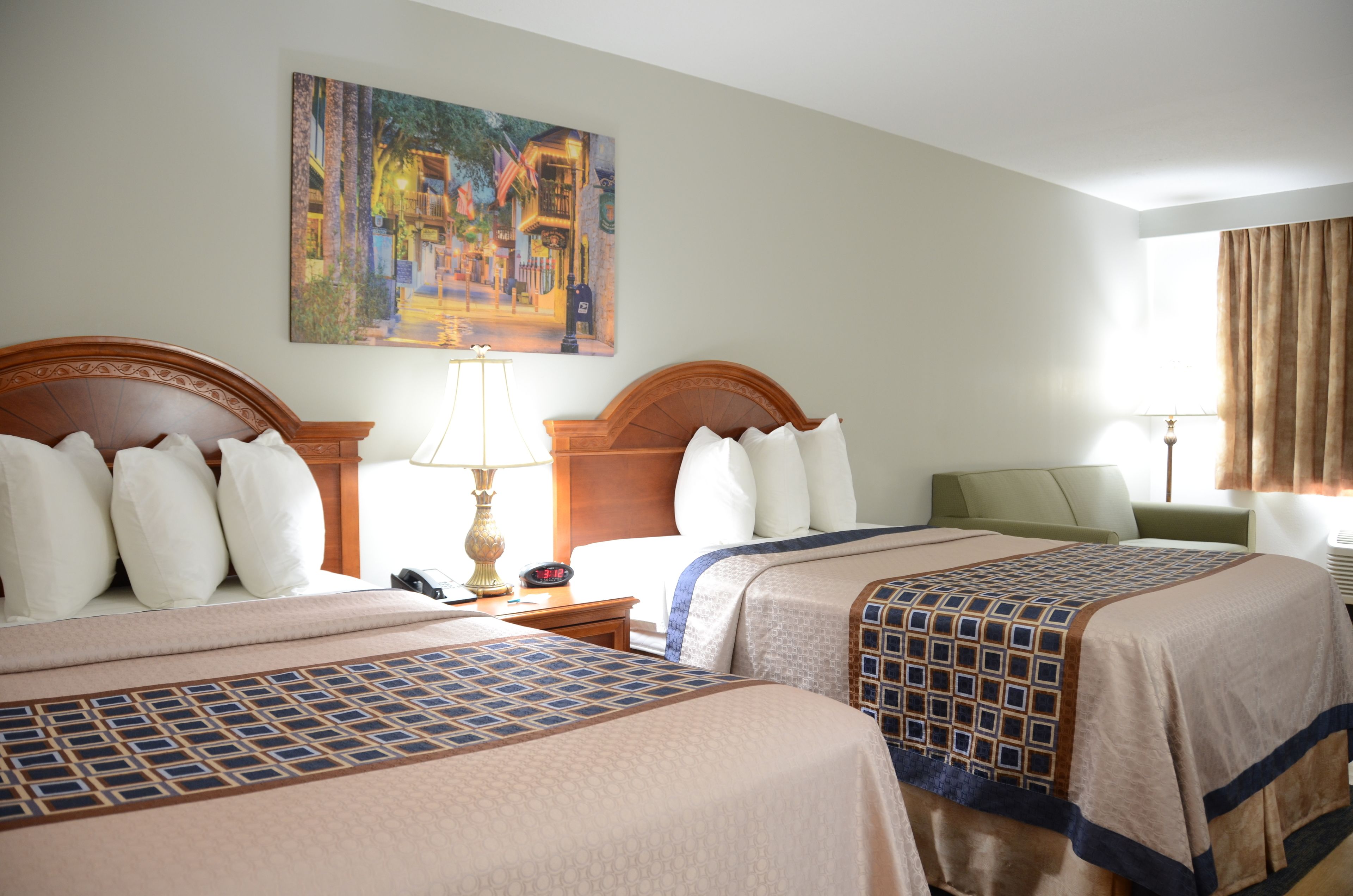 Una habitación de hotel con dos camas, un cuadro en la pared y una ventana con cortinas.