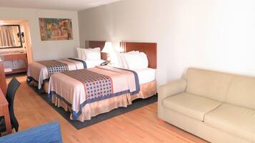 A hotel room with two beds, a sofa, a desk, and a chair.