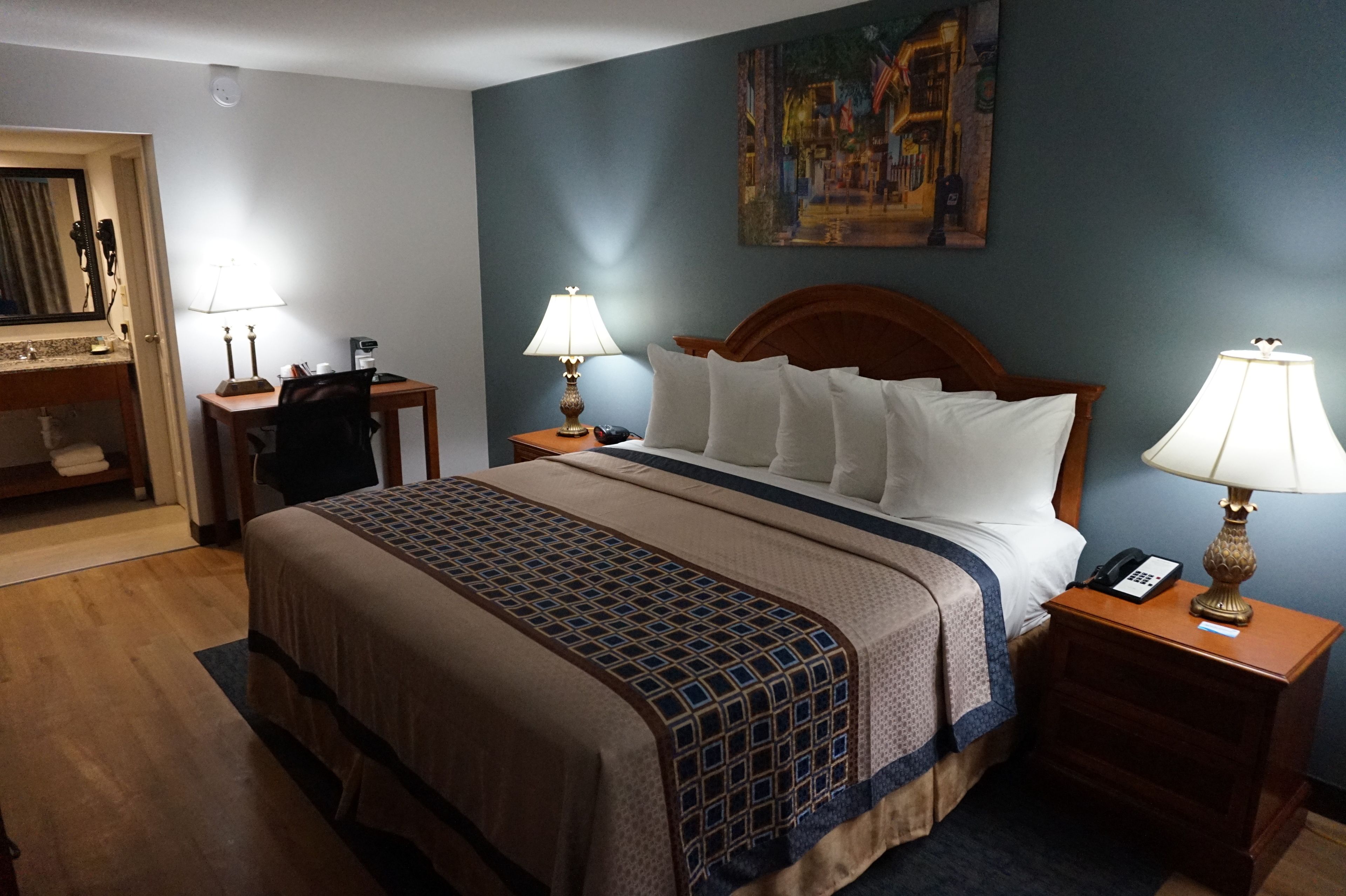 Une chambre d’hôtel avec un grand lit, deux tables de chevet avec des lampes, un bureau et une chaise.