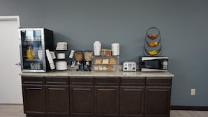 Una encimera de cocina con refrigerador, microondas, cafetera y diversos alimentos.