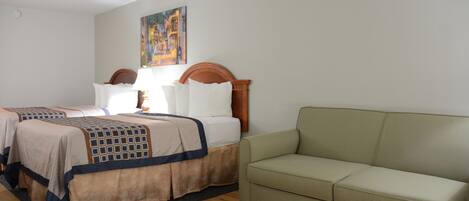 Ein Hotelzimmer mit zwei Betten, einem grünen Sofa und einem Gemälde an der Wand.