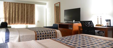 A hotel room with two beds, a desk, a chair, a television, and a window with curtains.