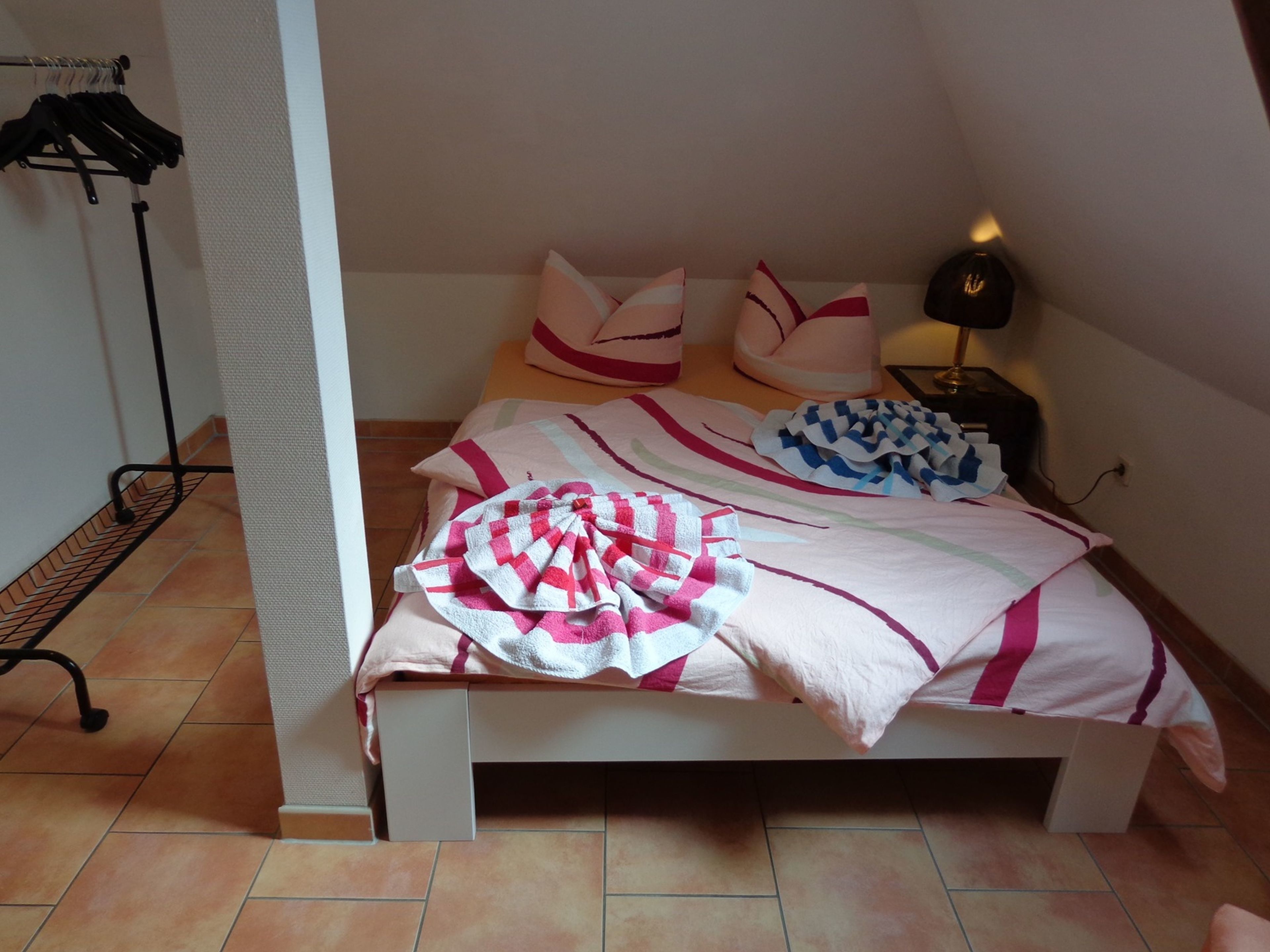 Une petite chambre à coucher, bien rangée, avec un lit, des oreillers et une table de chevet.