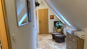 Um corredor com piso de azulejos que leva a um quarto com porta de madeira.
