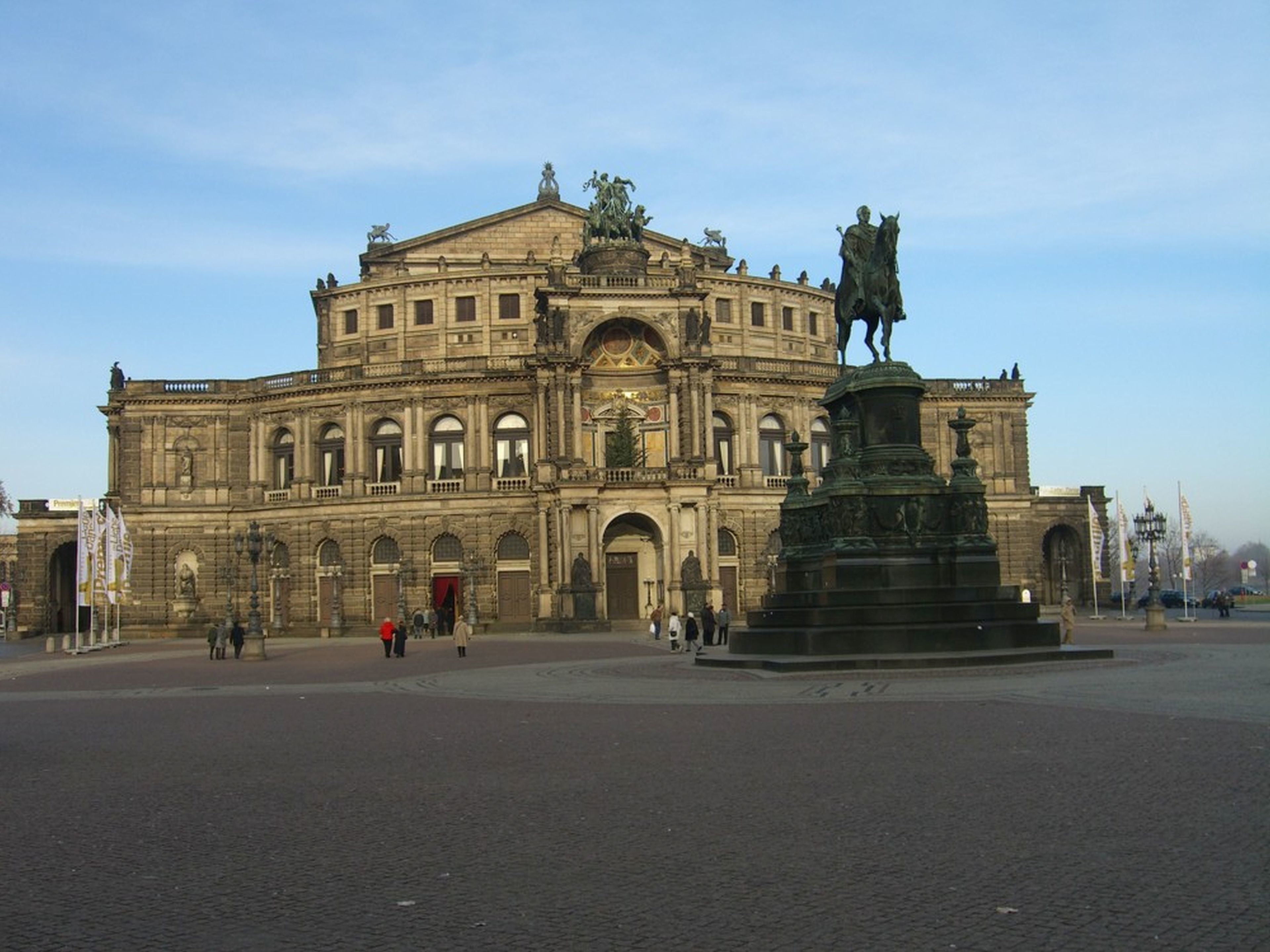 A historic building with a central statue and a fountain in front.