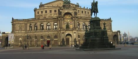 A historic building with a central statue and a fountain in front.