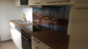 Uma cozinha moderna com fogão embutido, pia e um grande mural com vista para a cidade.