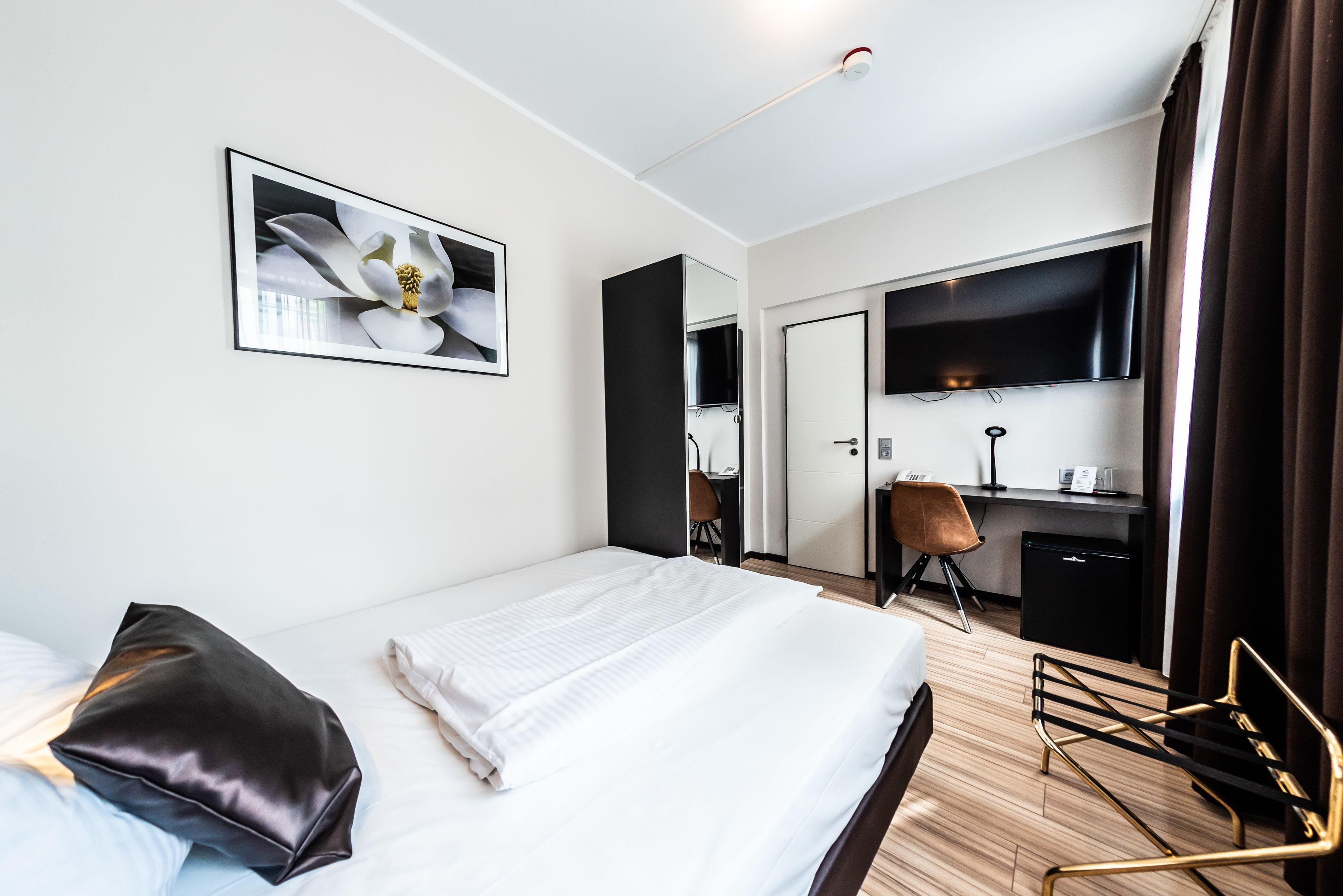Une chambre d’hôtel équipée d’un lit, d’un bureau, d’une chaise, d’une télévision et d’un miroir.