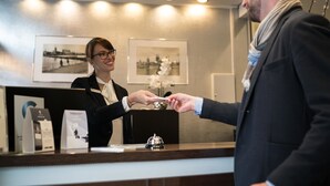 Una recepción de hotel con cuadros en la pared, un mostrador de recepción y una campana.