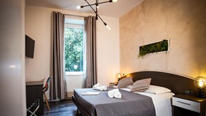A modern hotel room with a large bed, two bedside tables, a desk, and a chair. - Gate 40 (Rome)