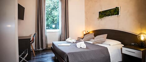 A modern hotel room with a large bed, two bedside tables, a desk, and a chair.