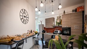 A modern kitchen with a dining area, featuring a clock, hanging lights, and various food items on the counter. - Gate 40 (Rome)