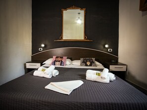 A neatly made bed with towels, a headboard mirror, and bedside lamps. - Gate 40 (Rome)