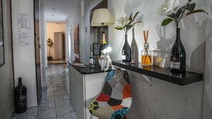 A modern kitchen with a black countertop, a colorful chair, and a vase with white flowers. - Gate 40 (Rome)