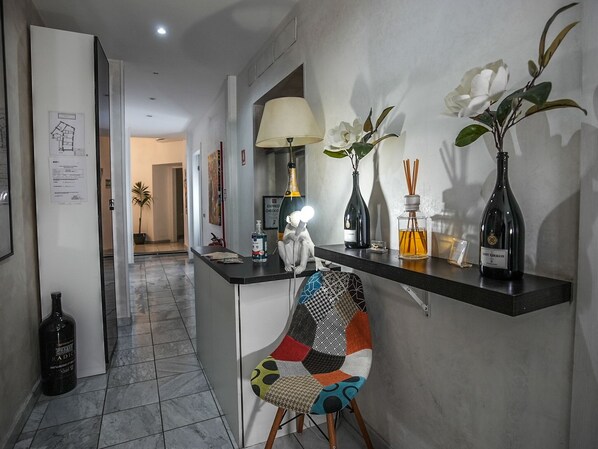 A modern kitchen with a black countertop, a colorful chair, and a vase with white flowers. - Gate 40 (Rome)