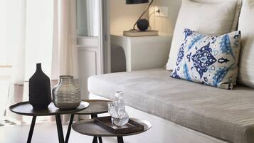 A modern living room with a grey sofa, a patterned pillow, a small round table with decorative items, and a floor lamp.
