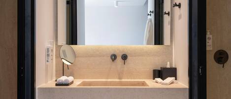 A modern bathroom with a large mirror, a sink, and a towel rack.