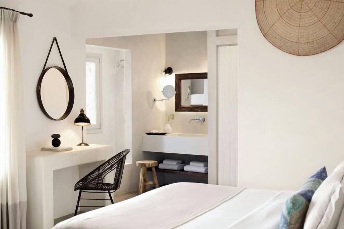 Ein Schlafzimmer mit Bett, Schreibtisch mit Stuhl, Schminktisch mit Spiegel und einer runden Wanddekoration.
