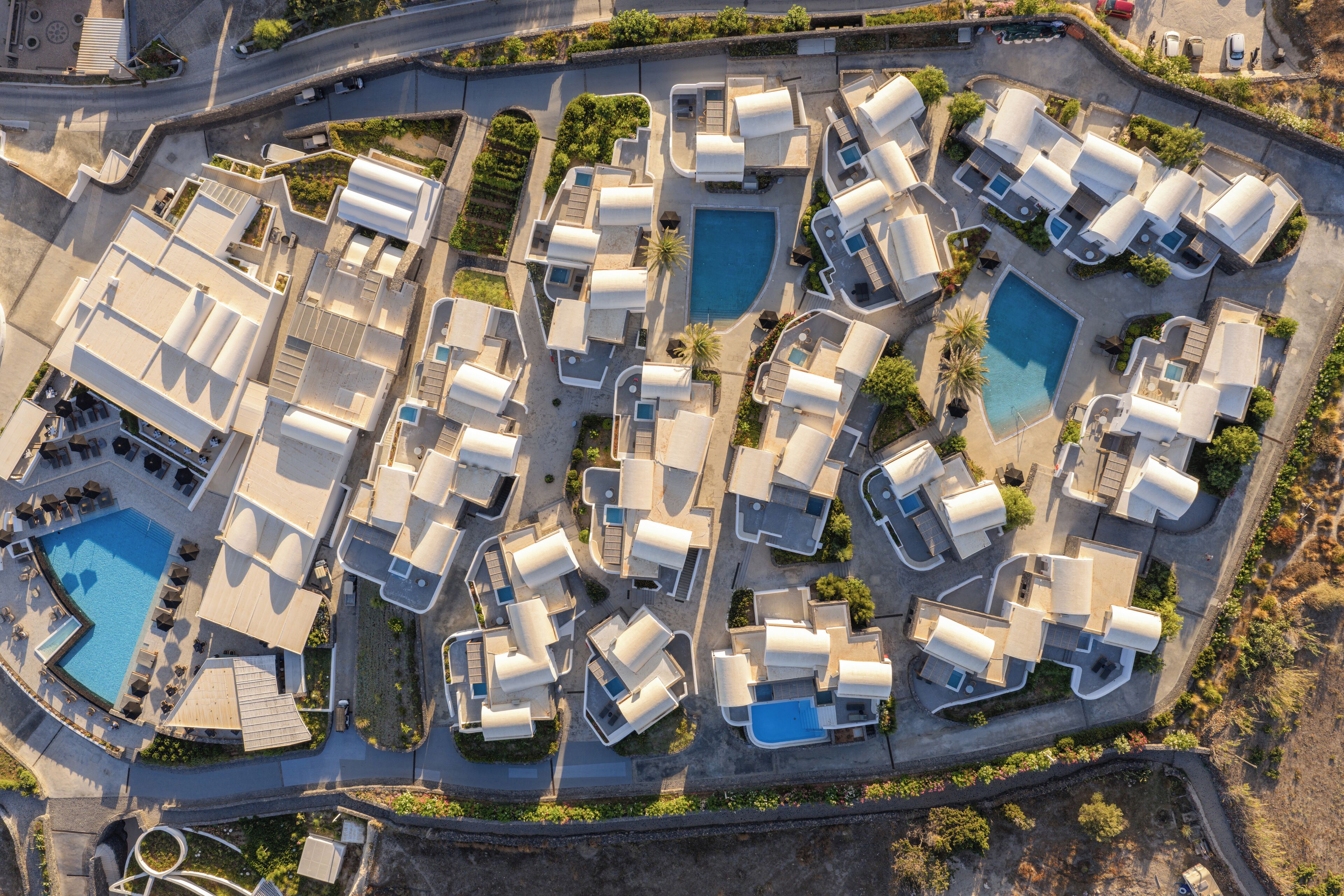 An aerial view of a resort with multiple bungalow-style accommodations, a central swimming pool, and landscaped areas.