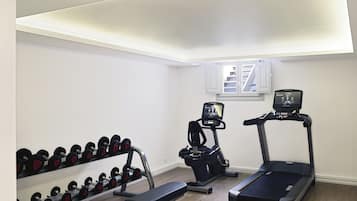 A home gym with a treadmill, elliptical, bench, and dumbbells.