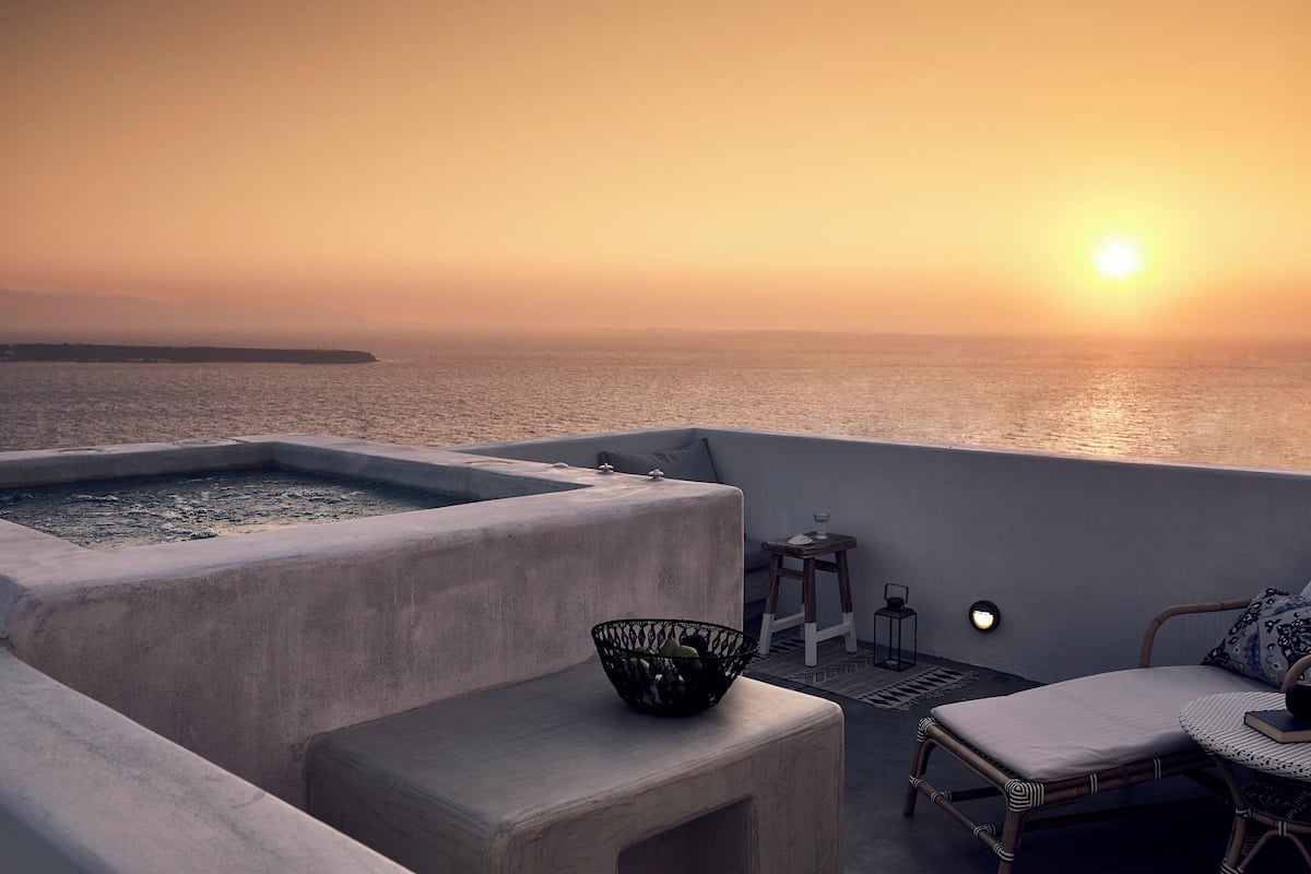 Eine Terrasse mit Whirlpool, einem kleinen Tisch mit Laterne und einem Korbstuhl.