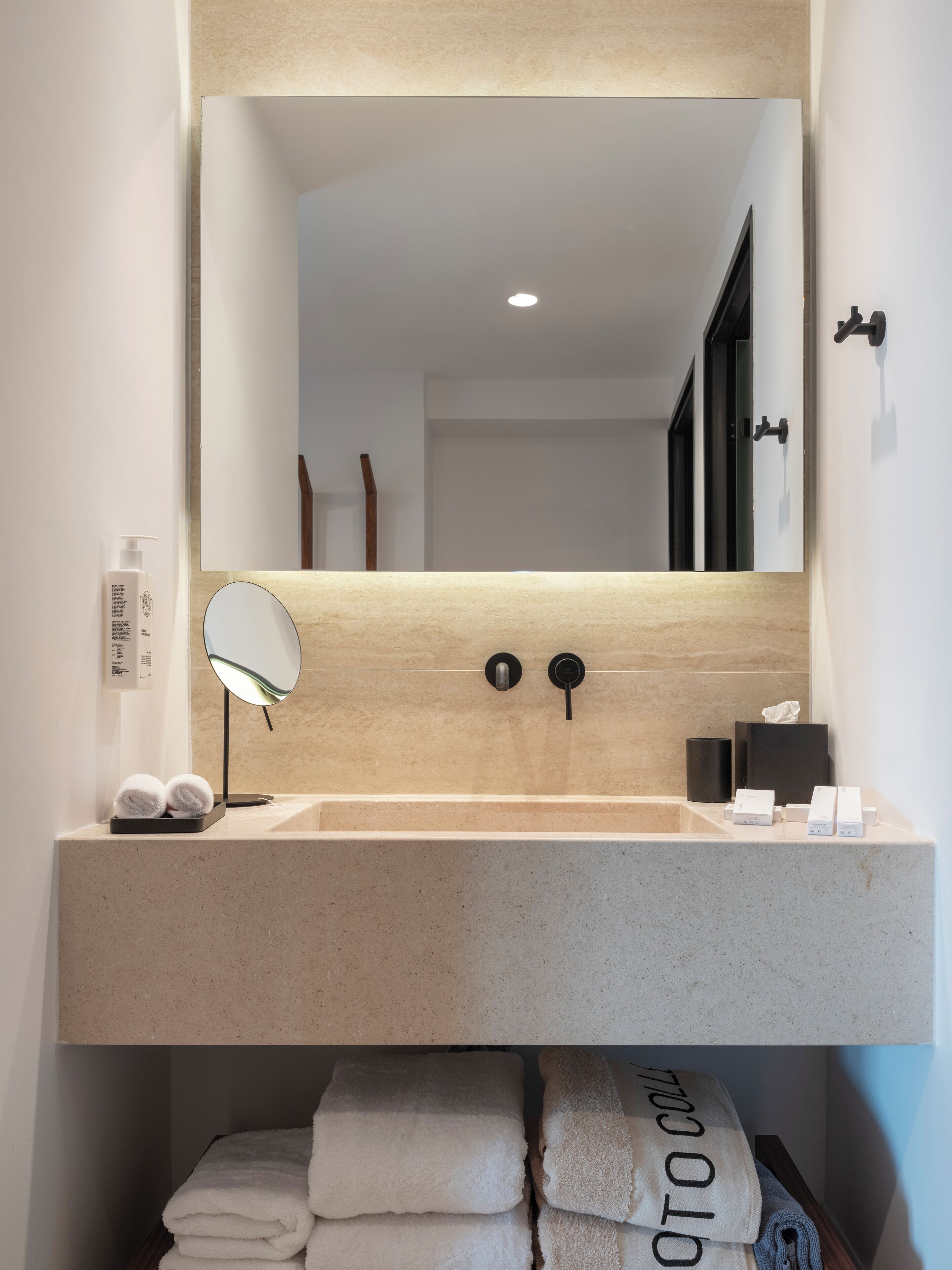 A bathroom with a large mirror, a sink, and a towel rack.
