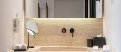 A bathroom with a large mirror, a sink, and a towel rack.