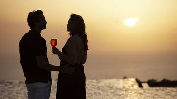A couple standing by the water during sunset.