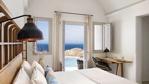 Un dormitorio con cama, escritorio y vista al mar.