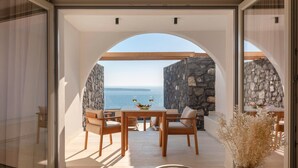 Un espacio moderno para comer al aire libre con una pared de piedra y vista al mar.