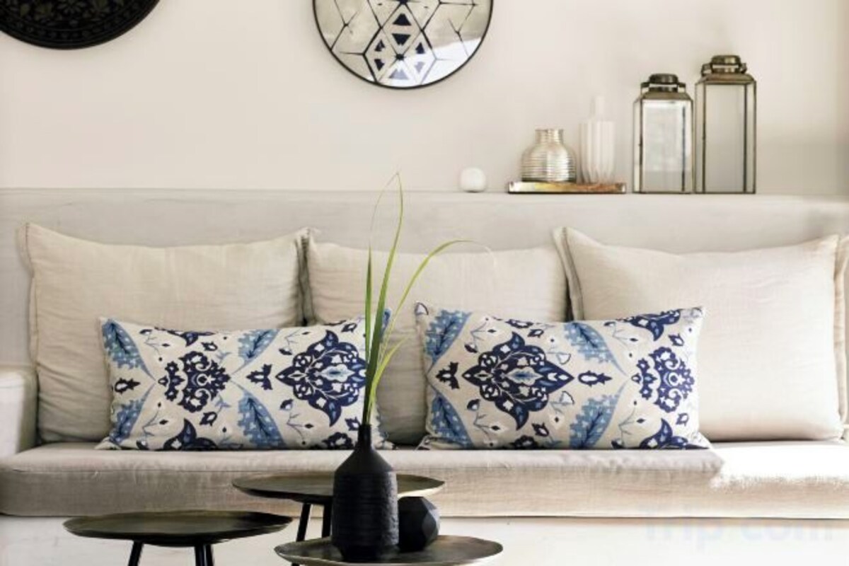 A sofa with patterned cushions, a vase with a plant, and a wall clock.