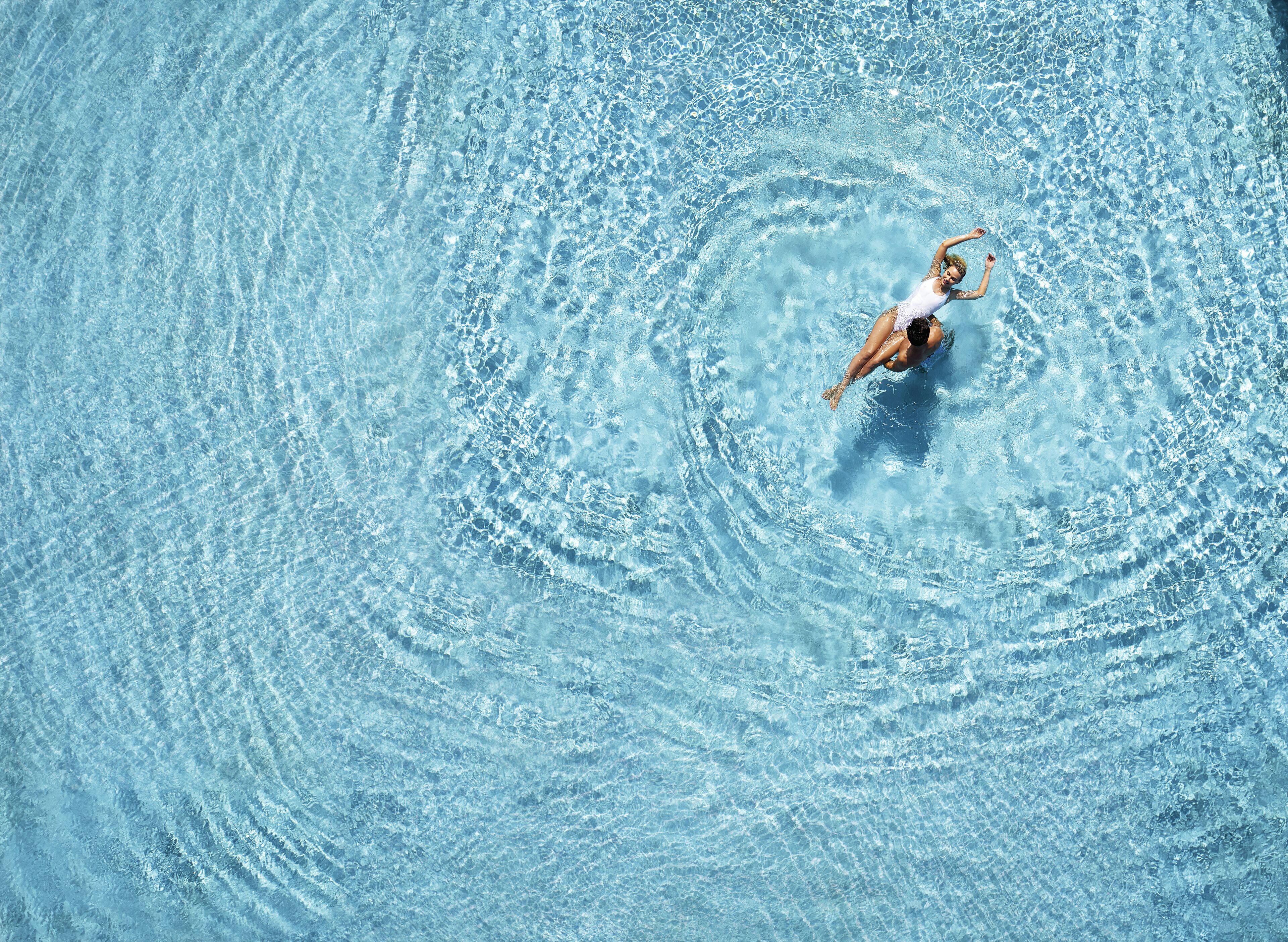 A person swimming in a clear blue pool.