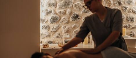 A massage therapy session in a room with a stone wall.