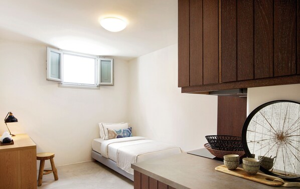 Un dormitorio pequeño y moderno con cama, escritorio y ventana.