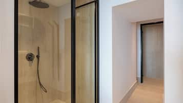 A modern bathroom with a glass-enclosed shower, tiled walls, and a wooden floor.