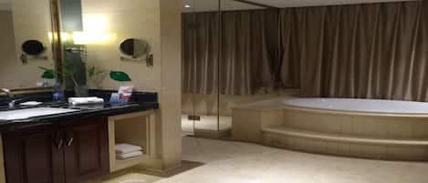 A modern bathroom with a large mirror, a bathtub, and a shower area.