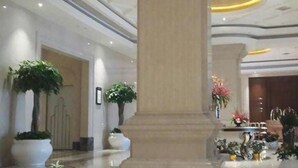 A spacious lobby with a large central column, potted plants, and a reception desk. - Jialaite Garden International Hotel (Nanchang)