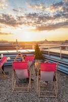 Een dak terras met zitgedeeltes en uitzicht op de ondergaande zon.
