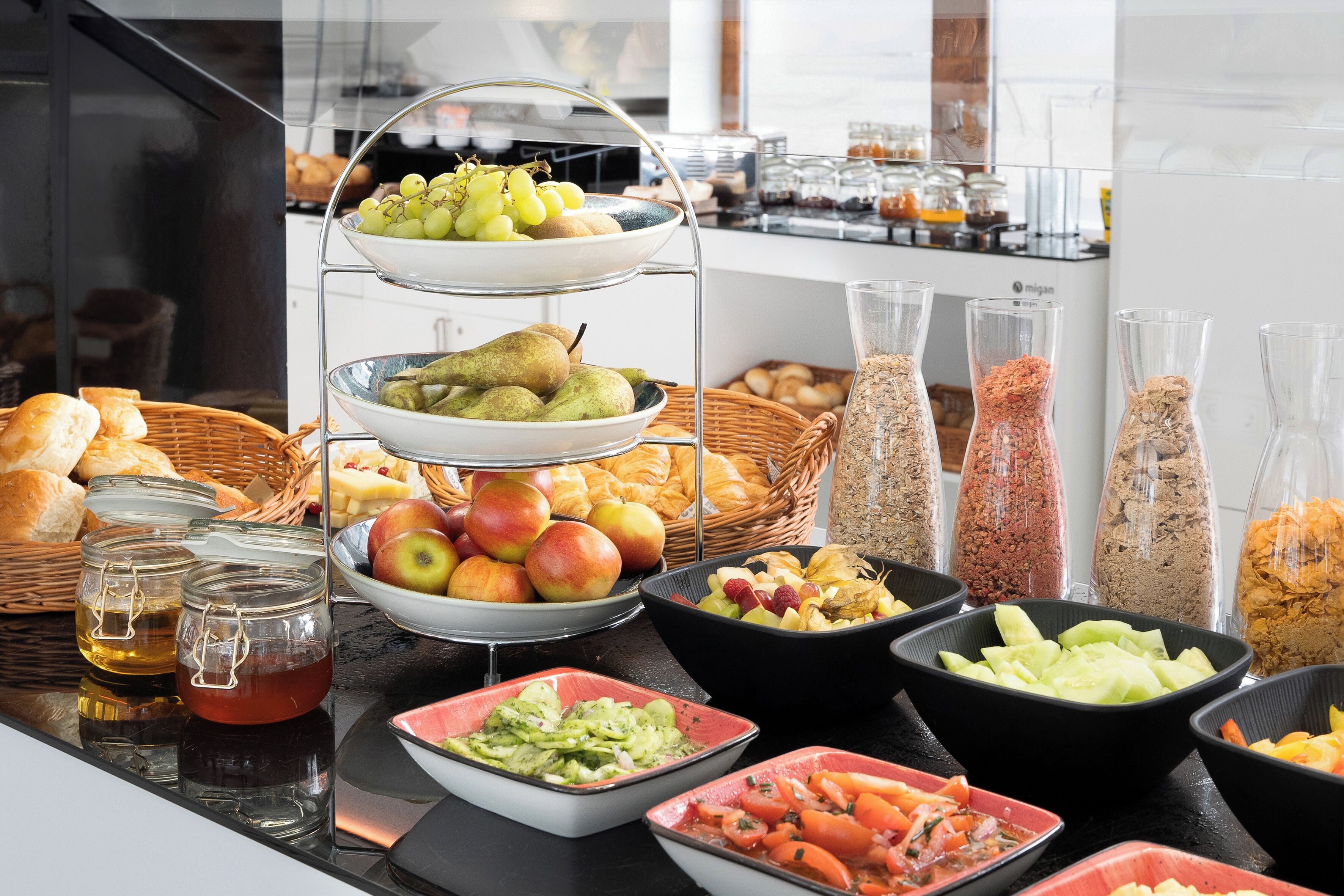 A buffet with various fruits, pastries, and condiments.